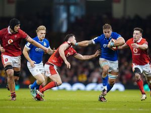 Italy player runs with the ball as a Wales player attempts to tackle