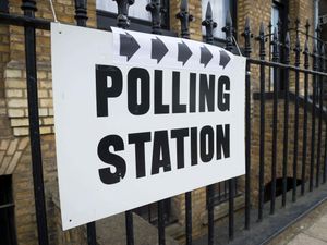 A polling station sign on a set of railings