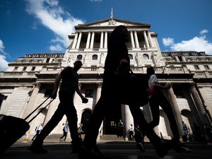 Silhouettes of people walking past the Bank of England