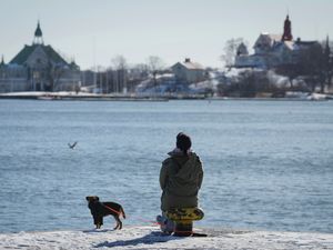 A woman enjoys a sunny and frosty day on the embankment of the South Harbour in Helsinki, Finland