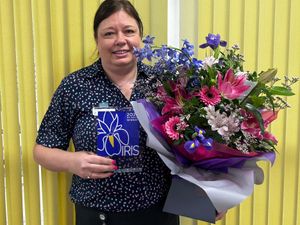 Joanne Jones, pictured with her IRIS Award and bouquet of flowers.