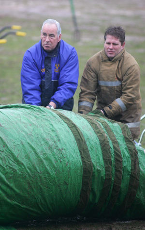 Roland Wycherley helps the fire brigade to roll up the pitch covers