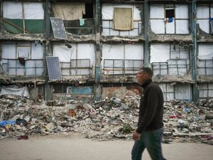 Man walks past destroyed building