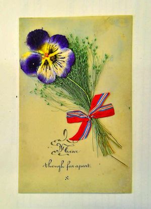 A pressed pansy decorated with ribbon and a special message to a loved one