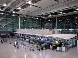 Passengers arrive with their luggage at a Lufthansa check-in counter at Munich Airport