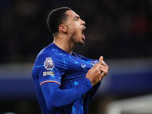 Levi Colwill grabs the badge on his Chelsea shirt while celebrating