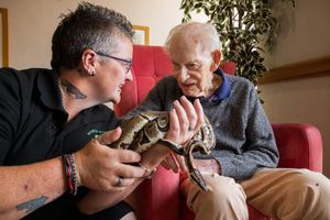 Sam Wright (Owner of The Mobile Mini Zoo) and Frank Telfer, 95 (Resident) with “Bob” a Royal Python