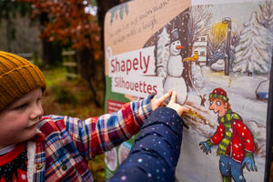 Children interacting with the Christmas Stick Man trail display boards.