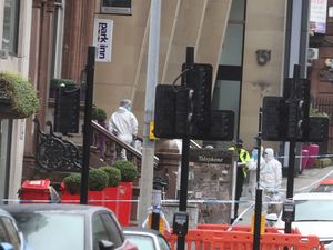 Forensic officers and police outside a hotel, which is taped off