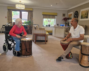 Resident at HC-One’s Perry Locks Care Home with Rico from Fitness Wellbeing in Care playing the African drums
