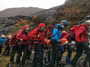 Search and rescue and ambulance crews carry the injured man to safety