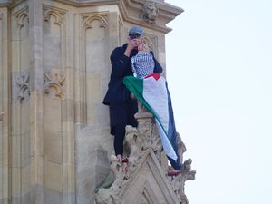 A man with a Palestine flag after he climbed up Elizabeth Tower,