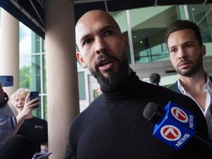 Andrew Tate speaking to the media as his brother Tristan stands behind him