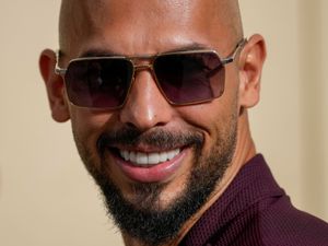 Headshot of Andrew Tate smiling, wearing sunglasses