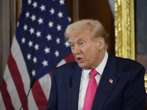Donald Trump speaks in front of an American flag