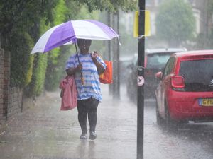 A person walks in the rain through Kentish Town, north London