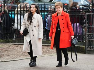 Nicola Sturgeon, in a red coat, arrives for the funeral