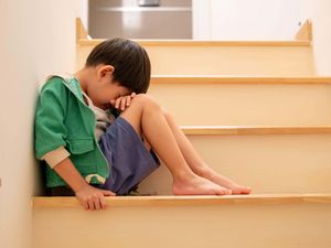 A young boy sits on some stairs crying