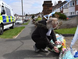 A woman puts flowers down outside the house on Boundary Avenue