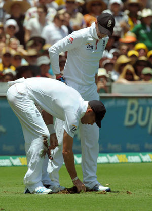 England's James Anderson replaces a piece of turf after slipping on the outfield