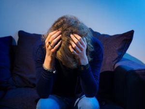 A distressed woman on sofa with her head in her hands