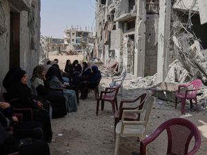 Palestinian women sit by the rubble of a house targeted by an Israeli army strike in Khan Younis