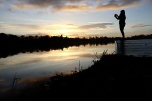 A runner stops to snap a photo of sunrise at the mere photo Sue Austin