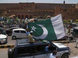 People cheering and waving Pakistani flags