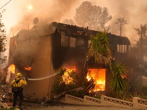 A firefighter tries to extinguish flames at a burning apartment building in Altadena, California