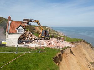 Supporting image for story: Farmhouse left hanging over cliff due to coastal erosion is demolished