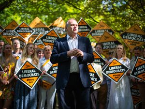Sir Ed Davey speaks in front of a group of supporters holding up Liberal Democrat signs
