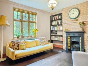 The lounge features exposed wooden floorboards, an ornate surround around the traditional gas fireplace set into an exposed brick chimney and a column radiator. Photo: Yopa