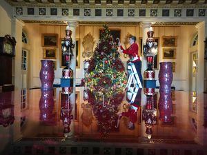 A worker adds a decoration to a large Christmas tree