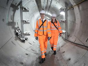Ed Miliband and Angela Rayner wearing orange hi-vis suits in an industrial setting