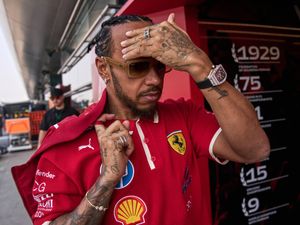 Lewis Hamilton wipes his forehead as he arrives in the paddock in Shanghai