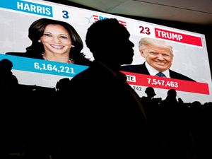 Kamala Harris and Donald Trump projected on a big screen at Howard University as students watch live election results during a watch party