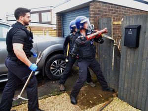 Police bash through a fence in Broseley as they swoop on a rural crime conspiracy suspect. 