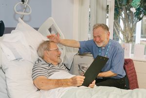 Being baptised from his hospital bed is Bill Starling (left), with RJAH’s Lead Chaplain, The Rev Simon Airey.