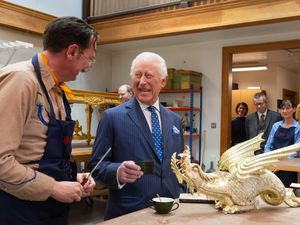 The King laughing as he chats to a gilder in front of an ornate dragon which is about to be gilded