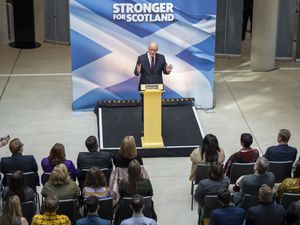 John Swinney talks from a podium during an SNP event