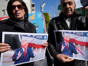 Palestinians carry defaced pictures of US President Donald Trump while protesting against his latest statements regarding the transfer of Palestinians from Gaza, in the West Bank city of Ramallah