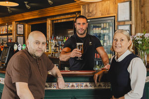 Community hero Craig Timmins pulls the first pint alongside pub partners, Paul and Dawn Newlands