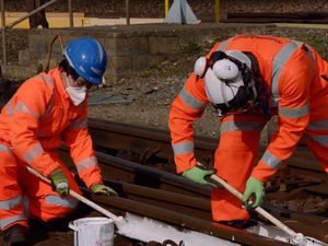 Rail track workers applying white paint to rails
