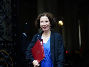 Anneliese Dodds smiling, walking outside with a ministerial red folder under her arm