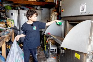 Image shows Ryan Hulance, who started We Can CIC (Community Interest Company) - an initiative to collect cans to help good causes, putting a can into a crusher in his garage at home in Solihull, West Midlands.