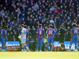 Crystal Palace’s Jean-Philippe Mateta receives treatment while surrounded by players.