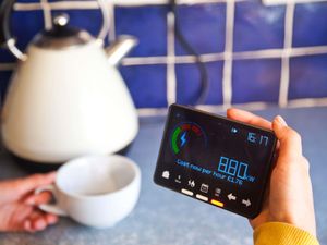 Person viewing a smart meter and holding a hot drink