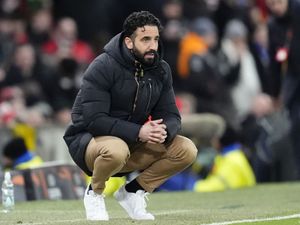 Manchester United manager Ruben Amorim crouches on the touchline