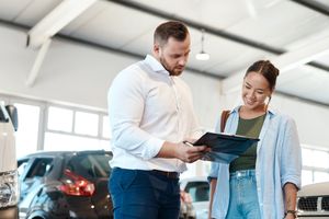 A car buyer discusses finance options with a dealership representative. New research suggests many UK drivers now regret the car finance deals they agreed to in the past decade.