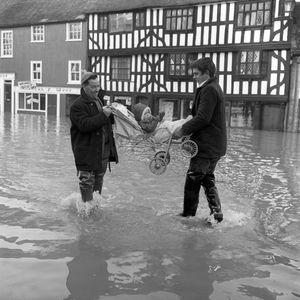 1968: Caroline Abell, a seventeen month old baby, is happily carried to safety through the deep and swirling flood waters at Frankwell, Shrewsbury.